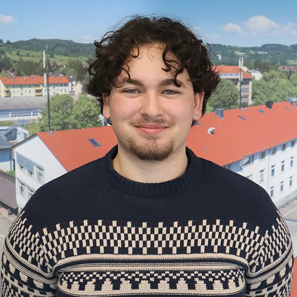 Junger Mann vor roten Dächern lächelt