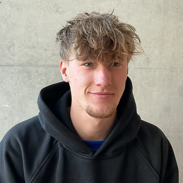 Junger Mann in Hoodie vor Betonwand.