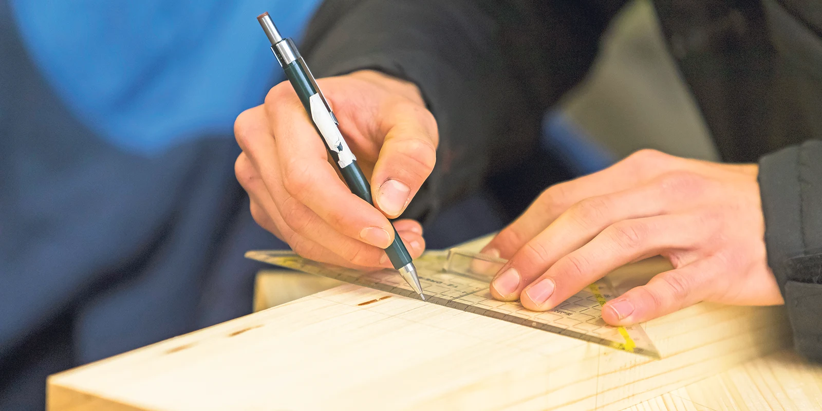 Person markiert Holz mit Lineal.