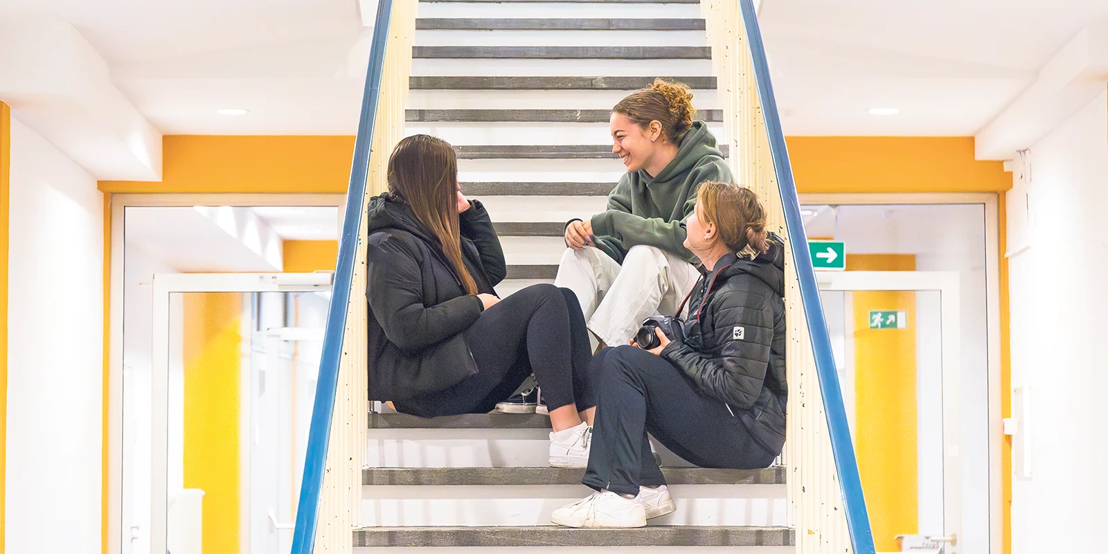 Drei Personen unterhalten sich auf Treppe